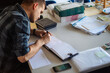 © Martin Sarovski/Stocksy - Man Writing in Logbook at Desk With Maps