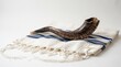 © Анастасия Макевич - Jewish shofar horn rests on a striped white tallit prayer shawl against a clean background with space for text