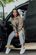 © anyatachka95 - Young woman in casual attire sitting in a car doorway on a sunny day.