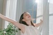 © Ryzhkov - Young Japanese woman taking a deep breath by a window, serene and refreshed with soft golden light and copy space for wellness content