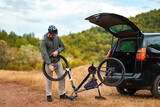 Fixing a bike tire near an open car in the great outdoors