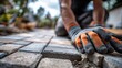© imageSTOCK - Faceless landscaper man laying interlocking paving stones in a garden area on a cloudy day