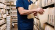 © Foyzul - Medical professional in blue scrubs organizing patient records in a filing room with shelves full of manila folders