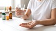 © Gradia - Person holding a glass of water and taking medication at a table with daily routine health issues health care managing health well being pain relief medical supply medicine