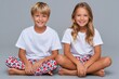© Gatherina - Happy children siblings sitting on floor wearing pajamas