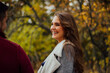 © anyatachka95 - Smiling woman enjoying conversation in autumn park.