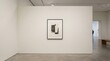 © Sim - A rectangular painting hangs on a white wall in a modern art gallery. The painting features a dark, abstract composition of geometric shapes.