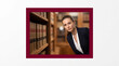 © ZaStock - Young woman in professional suit looking at camera in library, bookshelves filled with old books, serious expression, academic setting. Law, education, corporate, legal profession.