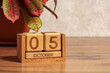 © Dmitrii Labrador - October 05, a wooden calendar made of cubes on the desktop with a houseplant. The concept of a deadline for a task, an important date.