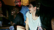 © ON - Studio - Diverse group of young adults laughing and enjoying a house party, illuminated by direct flash photography. Dark, intimate atmosphere. Social gathering and fun