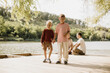 © BGStock72 - Two joyful boys holding hands on a serene lakeside deck in the afternoon