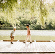 © BGStock72 - Children playing on a sunny wooden dock by a serene lake in summer