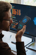 © Arsenii - Over-the-shoulder view, of man holding smartphone, talking with AI chatbot app, asking questions, using artificial intelligence assistant for work and daily tasks on phone and computer.