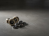 Skateboard wheels and bearings on concrete, surfaces showing honest wear and use, moody low-key light with a single highlight