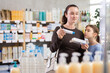 © JackF - Woman with schoolgirl daughter are busy choosing ointment at pharmacy, compare with other good. Curious girl watches her mother attentively, take part in shopping with mother