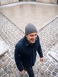 © AdPremium - Happy mature man in knit beanie and warm coat enjoying snowfall outdoors on a cobblestone street