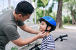 © Petr - Parent Fitting Bicycle Helmet on Child Outdoors