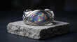 © BaqirAli - Ring featuring an iridescent opal stone set in an elaborate silver band displayed on stone.