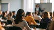 © haemye - Diverse group of business people attending a seminar or training session with a woman presenting