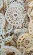 © Sobirin - A close-up shot of numerous white, circular, crunchy snacks with a delicate, intricate pattern, showcasing their unique texture and appetizing appearance