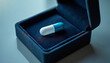 © Tassya - Blue and white medicine capsule pill inside open luxury jewelry box. Expensive healthcare and pharmaceutical cost concept