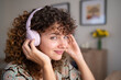 © Metadancer - White woman enjoying music on headphones at home with flowers
