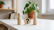 © Hasibul - Two wooden peg dolls standing on a white table with a speech bubble containing a question mark between them, representing communication or questions