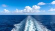 © PhamHuu - White Wake Trail of a Boat Crossing the Open Blue Sea Under a Cloudy Sky