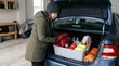 © rdkcho - Woman Preparing Winter Emergency Kit in Car Trunk