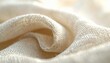 © ernawatima - Close-up of soft white woven fabric with a detailed textured surface, gently folded to create smooth curves and subtle shadows in natural light