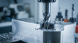© Dzunstock - CNC milling machine cutting a metal block, producing shiny metal shavings in a precision industrial workshop.