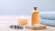 © Алла Морозова - Glass bottle of essential oil on a wooden spa tray, accompanied by a lit candle and lavender sprig, suggesting aromatherapy and relaxation therapy.