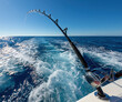 © poramin - Fishing rod ocean boat sea wave water sport fishing travel blue fishing rod bending over open ocean from moving boat, foaming wake trailing behind clear bright blue sky, dynamic outdoor adventure