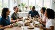 © Alex Pios - Diverse group of happy friends enjoying a healthy meal and lively conversation around a dining table at home, concept of friendship and healthy living