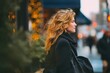 © Halyna - A woman is out on the city street during the holidays, enjoying the winter and the beautiful golden lights. The jacket she's wearing is black, and her hair is blonde and wavy