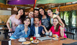 © Marcos - Group of Latino teamwork gathered together for brainstorming in cafeteria using laptop and notebook at breakfast time. young hispanic people woman and men working in Mexico Latin America