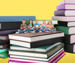 © New Africa - Cute little children sitting on stack of books against pastel yellow background
