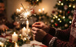 © SimpleDesignStudio - Young adult male holding burning sparkler during cozy Christmas dinner celebration at home