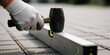 © MT - A gloved worker using a rubber mallet and spirit level to install paving stones outdoors