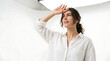 © Alif - Young woman shielding her eyes from bright light looking ahead while wearing casual white shirt