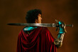 © AnnaStills - Rear view of young adult Caucasian knight holding sword on shoulder, looking sideways. Ideal for gaming promotion, fantasy marketing and theatrical productions