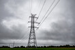 © ugis - Tall electricity transmission tower and power lines silhouetted against a dramatic overcast sky, creating a stark industrial atmosphere with ample copy space