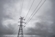 © ugis - Tall electricity transmission tower and power lines silhouetted against a dramatic overcast sky, creating a stark industrial atmosphere with ample copy space