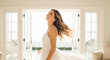 © susral - Graceful woman in flowing white dress dancing near sunny window perfect for joyful movement and elegant feminine lifestyle expression