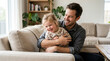© Liberty - Happy father and daughter laughing on sofa in modern living room
