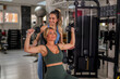 © DusanJelicic - Woman lifting dumbbells at gym while personal trainer provides guidance and encouragement, focusing on proper form and technique during a strength training workout