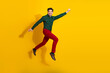 © deagreez - Young man jumping with joy against a bright yellow background wearing a green patterned shirt and red pants
