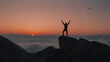 © Abigail - Man standing on cliff edge raising hands at colorful sunset sky