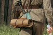 © Dmitry - A person wearing a vintage military uniform carries a portable radio transceiver, a brown leather map case, and a rolled canvas mat