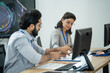 © winnievinzence - Colleagues collaborate on AI project in a computer workspace, sharing ideas and reviewing paperwork together to achieve common goals and build strong teamwork in a professional environment.